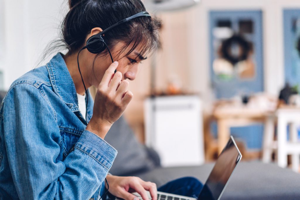 Young smiling happy beautiful asian woman relaxing using laptop computer working and video conference meeting at home.Young creative girl talk with headset.work from home concept